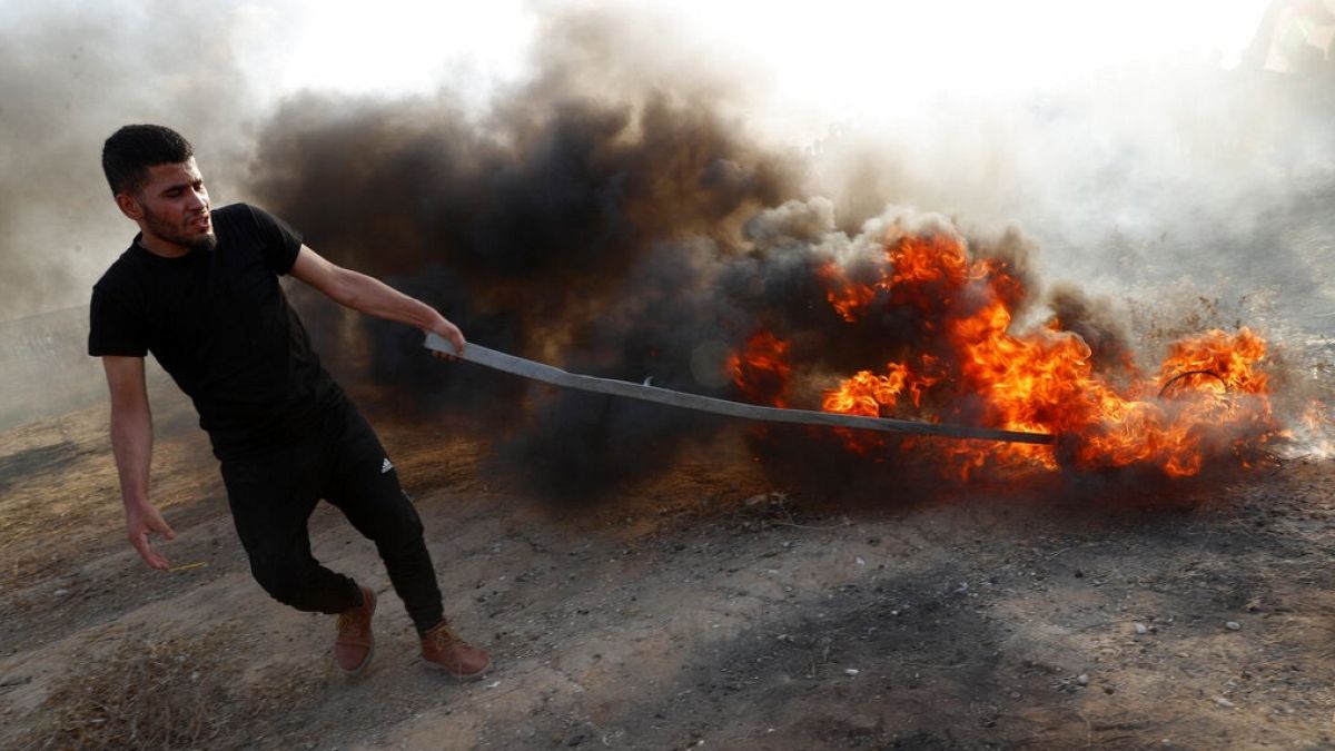 Égő gumiabroncsot húzó palesztin férfi egy korábbi tüntetésen