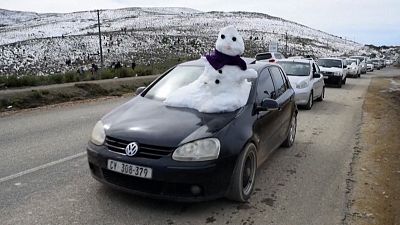 Snowman on the front of a car as it drives by.