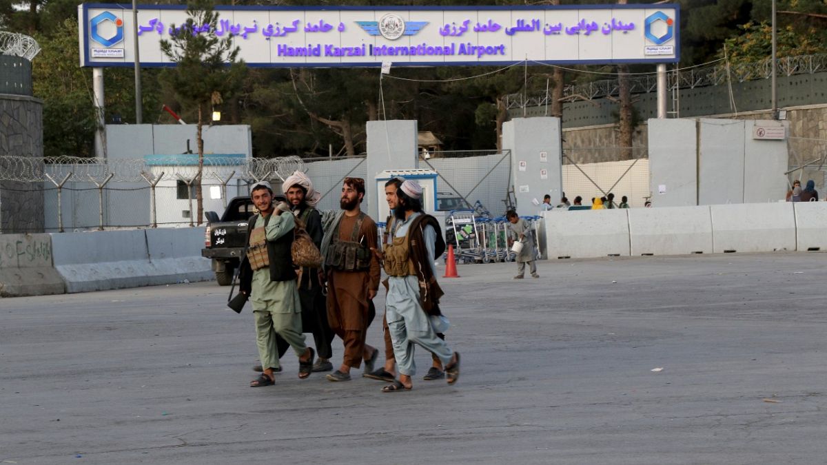 مقاتلو طالبان يسيرون أمام بوابة مطار حامد كرزاي الدولي في كابول، أفغانستان. 