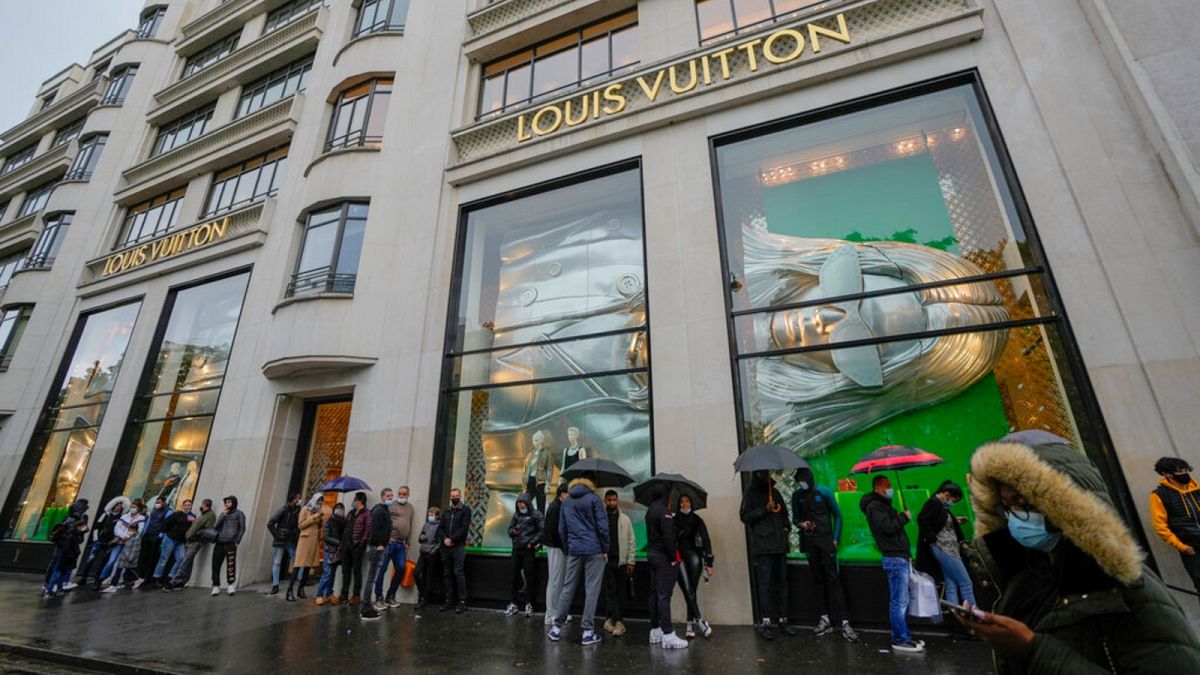 People line up as they wait to get in the Louis Vuitton shop on the Champs Elysee avenue in Paris, Wednesday, May 19, 2021
