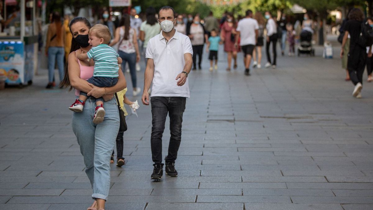 Pedestrians wear face masks through Mother Teresa square in Kosovo's capital Pristina.