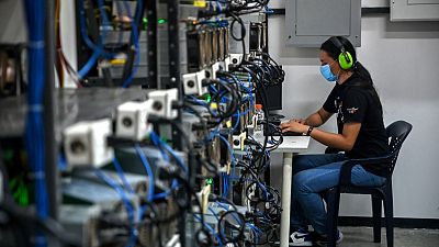 An employee inspects computers used to mine Bitcoin at the mining showroom of the Doctor Miner company in Caracas on August 18, 2021.