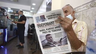 رجل يقرأ جريدة عنوانها الرئيسي إيقاف رجل الاعمال التونسي نبيل القروي في مدينة تبسة الجزائرية. 2021/08/31