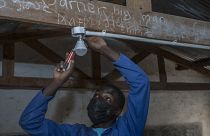 self-taught electricity producer Colrerd Nkosi fixes a bulb in a Standard Eight Class to light the classroom with electricity generated by Nkosi's hydro-powered turbine.