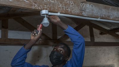 self-taught electricity producer Colrerd Nkosi fixes a bulb in a Standard Eight Class to light the classroom with electricity generated by Nkosi's hydro-powered turbine.