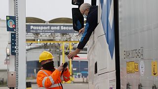 A lorry driver's documents are scanned on a phone as he passes a checkpoint for the train through the Eurotunnel link with Europe