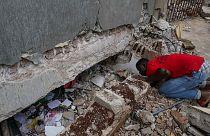 Um homem olha pelo buraco aberto numa escola afetada pelo sismo