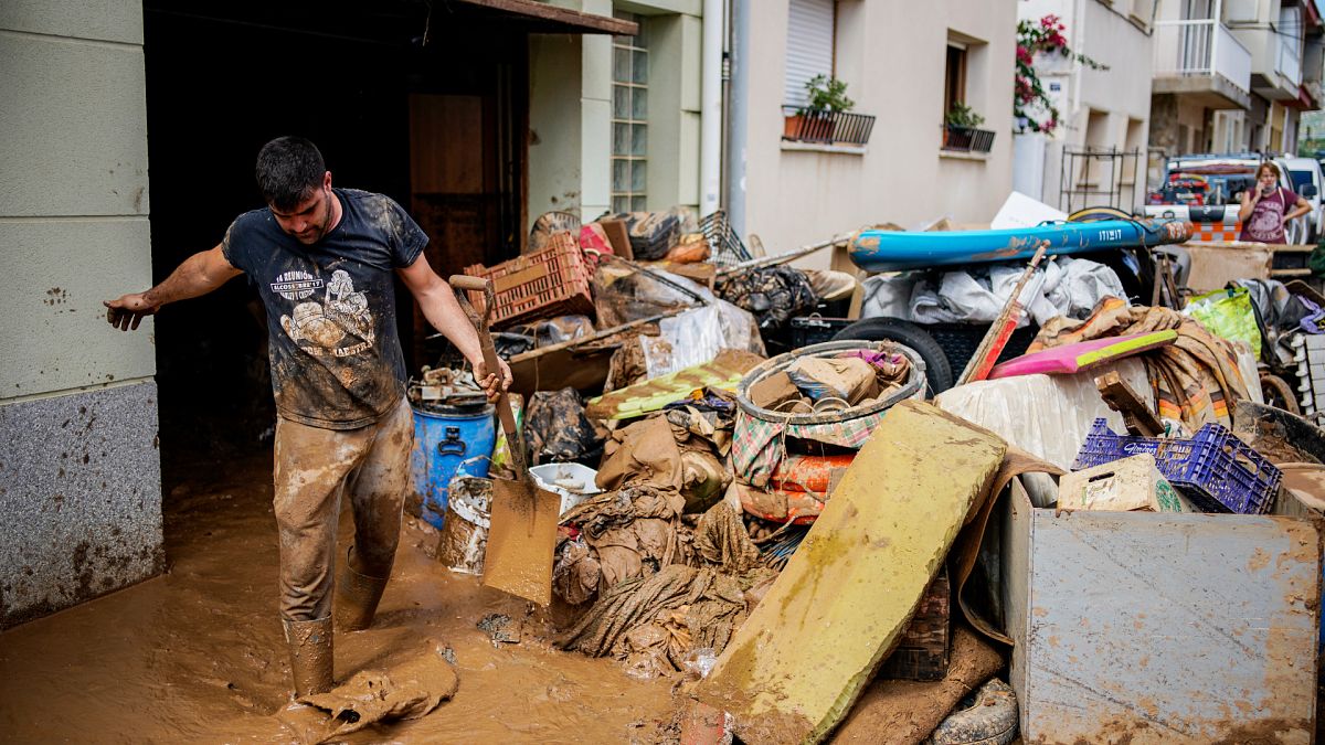 A man cleans up mud after flooding in a seaside town of Alcanar
