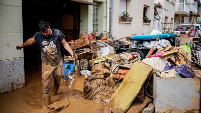 A man cleans up mud after flooding in a seaside town of Alcanar