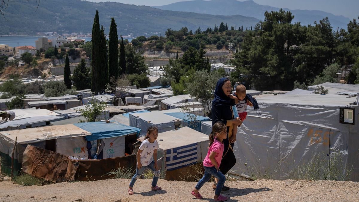 An Afghan woman with her three children walk outside the perimeter of the refugee camp at the port of Vathy on the eastern Aegean island of Samos, Greece, June 11, 2021.