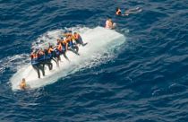 Migrants clinging to an overturned boat