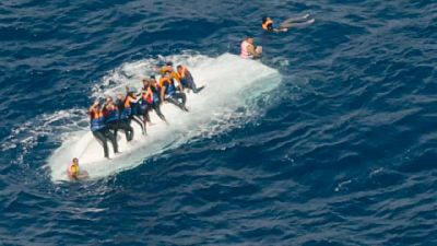 Migrants clinging to an overturned boat