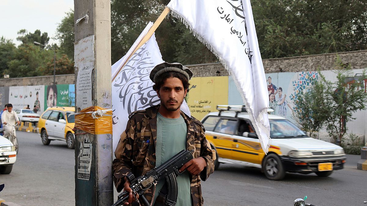 Un combatiente talibán sostiene su arma bajo las banderas talibanes colgadas en una calle de Kabul, Afganistán, el 30 de agosto de 2021.