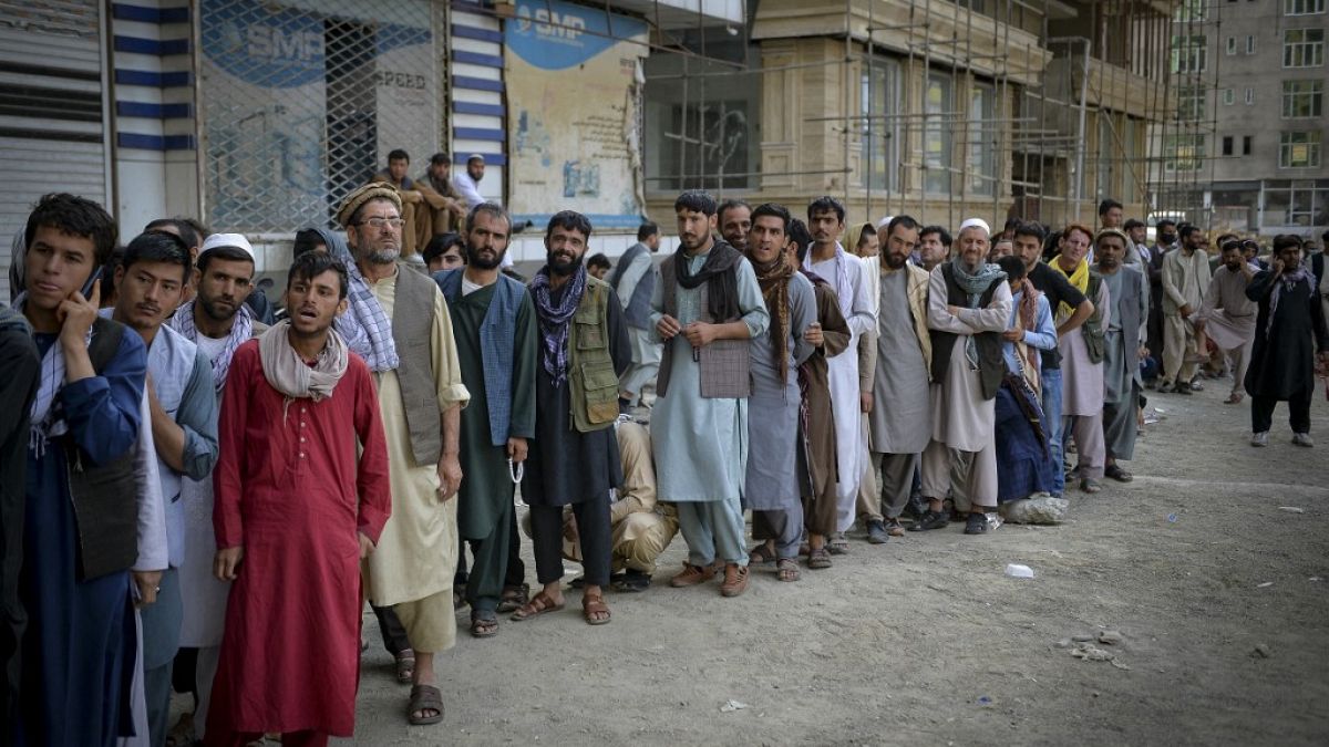 Afghans queue up as they wait for the banks to open and operate at a commercial area in Kabul on August 31, 2021.