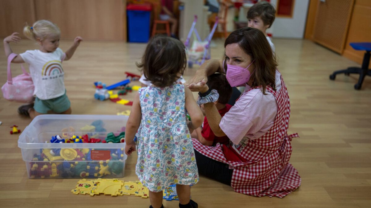 A teacher wearing a face mask to protect against the spread of coronavirus reacts with children in a class, at Vallehermoso school