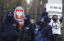 Police surround a protester who holds a sign saying in front of the Constitutional Court in Warsaw, Poland, Wednesday March 10, 2021