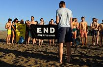 Participants gather and hold a banner on a beach in Marseille to draw the attention of world leaders and protest against the environmental crisis.