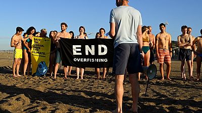 Participants gather and hold a banner on a beach in Marseille to draw the attention of world leaders and protest against the environmental crisis.