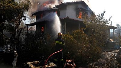 A firefighter tries to extinguish the flames at a burning house 60 kilometers northwest of Athens, Greece A firefighter tries to extinguish the flames at a burning house 60 kilometers northwest of Athens, Greece