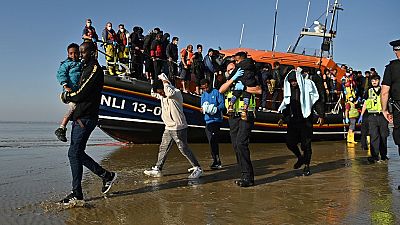 Migrants with children are escorted to be processed after being picked up by an RNLI lifeboat.