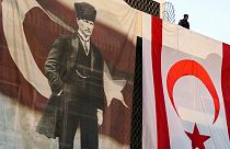 A member of the security forces stands above a large Turkish Cypriot flag and poster of modern Turkey's founder Mustafa Kemal Ataturk.