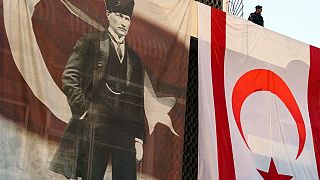 A member of the security forces stands above a large Turkish Cypriot flag and poster of modern Turkey's founder Mustafa Kemal Ataturk.