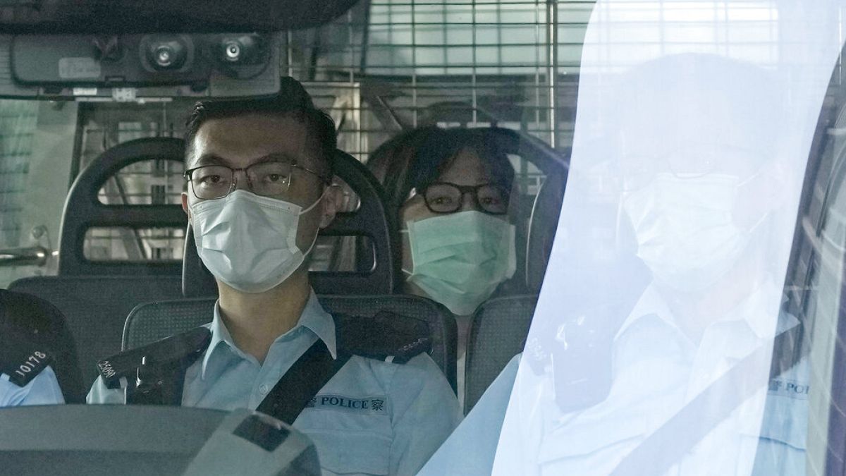 Chow Han Tung, vice chairwoman of the Hong Kong Alliance in Support of Patriotic Democratic Movements of China, center, is escorted by police in a van to a court, in Hong Kong