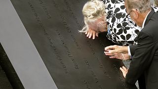 A woman cries over a name on the edge of the south pool at the National September 11 Memorial in New York on 10th anniversary, Sept 11 2011