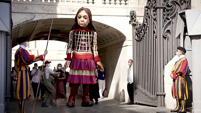 El papa saluda a la pequeña Amal, la marioneta gigante que representa a una niña refugiada siria