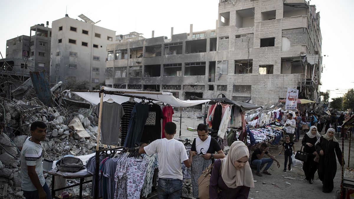 باعة فلسطينيون متجولون يعرضون سلعهم بالقرب من المباني التي دمرتها الغارات الإسرائيلية. 2021/07/18