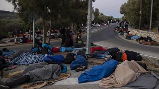 In this Thursday, Sept. 10, 2020, file photo, refugees and migrants sleep on a street near the destroyed Moria camp following a fire, on Lesbos island, Greece.