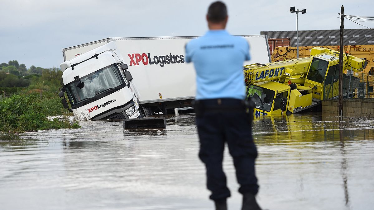 A French Gendarme officer looks at two trucks blocked in a flooded road in Codognan, in the Gard department, in the Occitanie region, southern France, on September 14, 2021