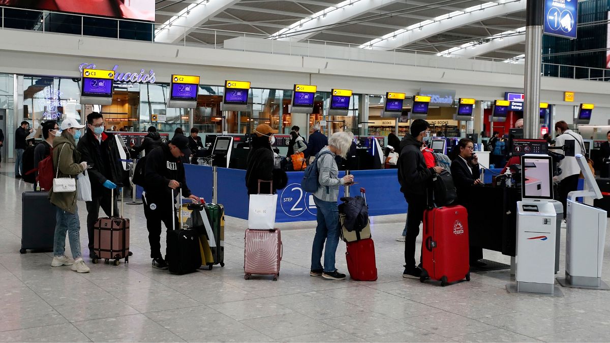 People queue at ticket machines at Heathrow airport in London, Wednesday, March 18, 2020. 