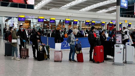 People queue at ticket machines at Heathrow airport in London, Wednesday, March 18, 2020.