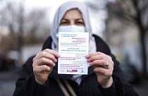 Aliye Tuerkyilmaz a member of a multilingual team of five street workers shows an information flyer as she poses for a photo in Berlin, Germany, Tuesday, March 9, 2021.