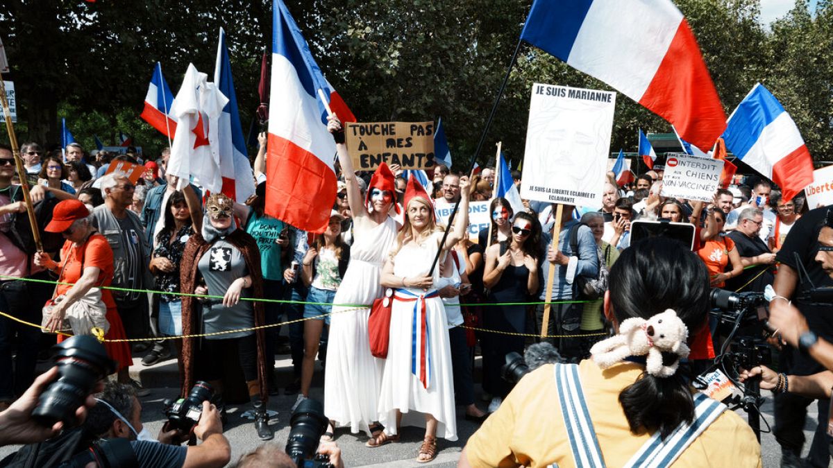 Protesters dressed as Marianne, the symbol of the French Republic since the 1789 revolution, are pictured by photographers during a demonstration against the health pass