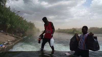 Men carry bags as migrants, many from Haiti, cross the Rio Grande near the Del Rio-Acuna Port of Entry in Del Rio, Texas, USA.