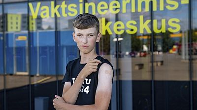Joonas Leis , 12 years old boy, poses for a photo after getting a shot a coronavirus vaccine at a vaccination center inside a sports hall in Estonia.