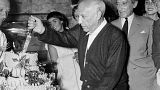 Spanish painter Pablo Picasso, flanked by his French friend poet Jean Cocteau (R), cuts his cake for his 75th birthday on October 25, 1956 in Vallauris.