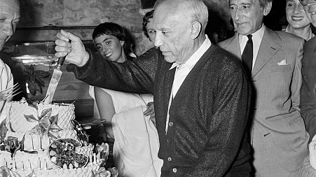Spanish painter Pablo Picasso, flanked by his French friend poet Jean Cocteau (R), cuts his cake for his 75th birthday on October 25, 1956 in Vallauris.