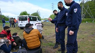عناصر من الشرطة الفرنسية يتحدثون مع مهاجرين عراقيين في مخيم غراند سينث في مخيم كاليه.