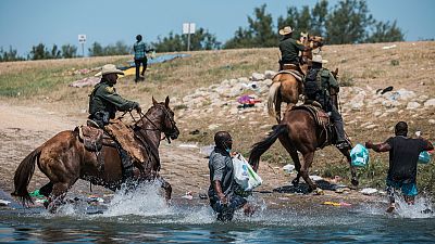 ضباط الجمارك وحماية الحدود الأمريكية يحاولون احتواء المهاجرين أثناء عبورهم ريو غراندي من سيوداد أكونيا في المكسيك إلى ديل ريو في تكساس.