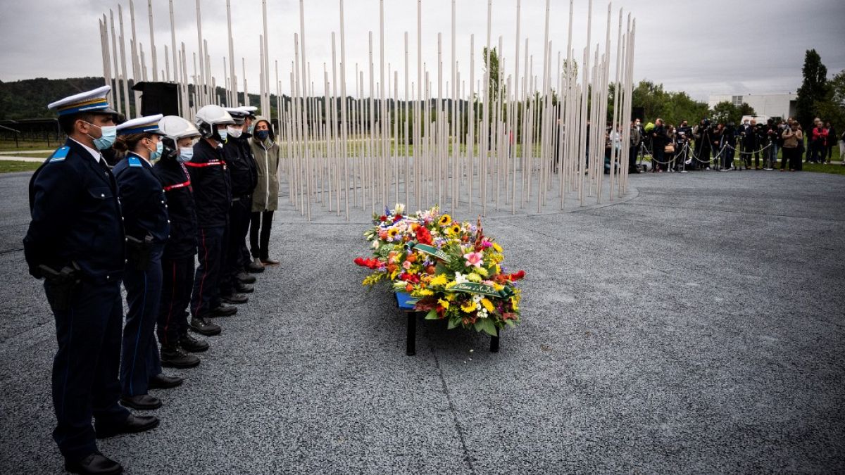 Policemen and firemen stand at a monument dedicated to the victims of the explosion.