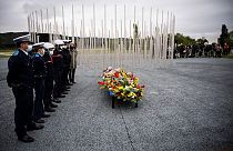 Policemen and firemen stand at a monument dedicated to the victims of the explosion.