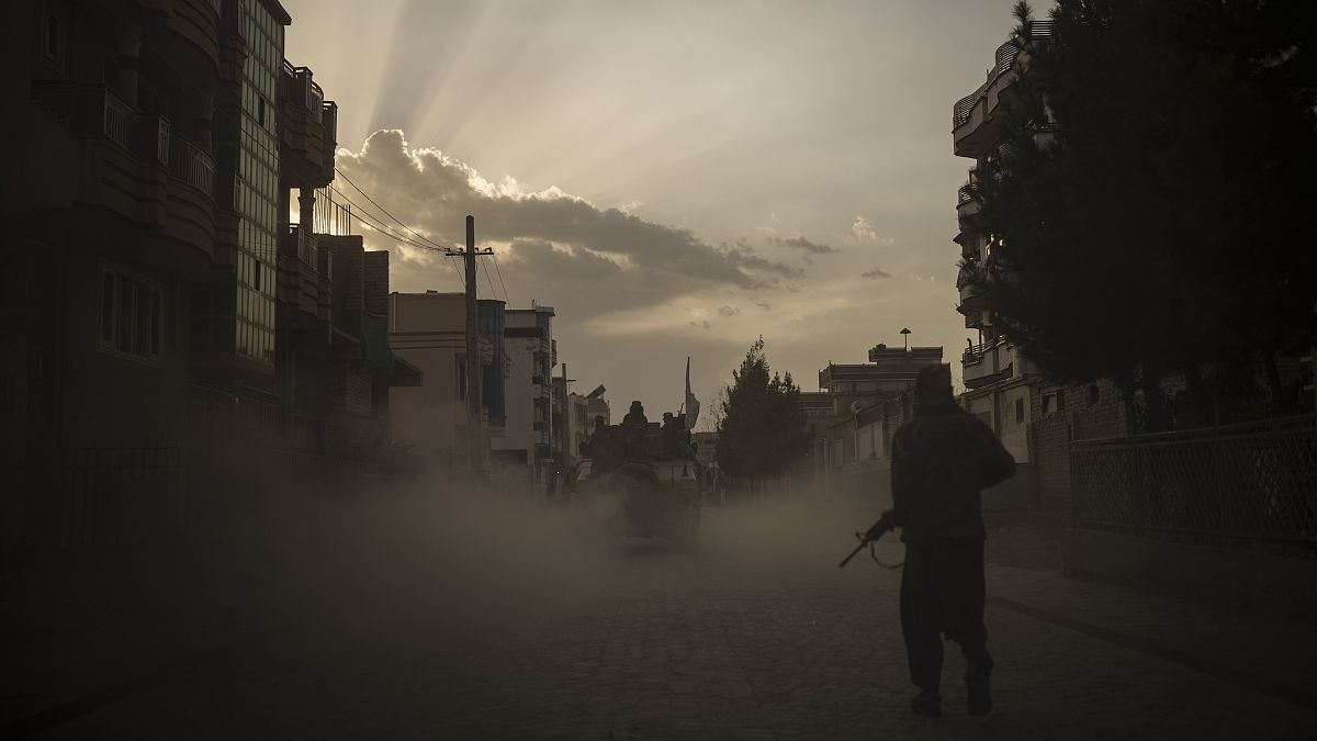 مقاتل من طالبان يمشي على جانب طريق فيما سيارة هامفي تحمل مقاتلين آخرين في كابل. 2021/09/21