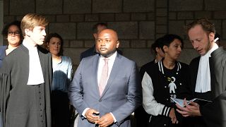 Mpanzu Bamenga, centre, stands with his legal team and rights activists outside a courtroom at The Hague District court, Netherlands, Sept. 22, 2021