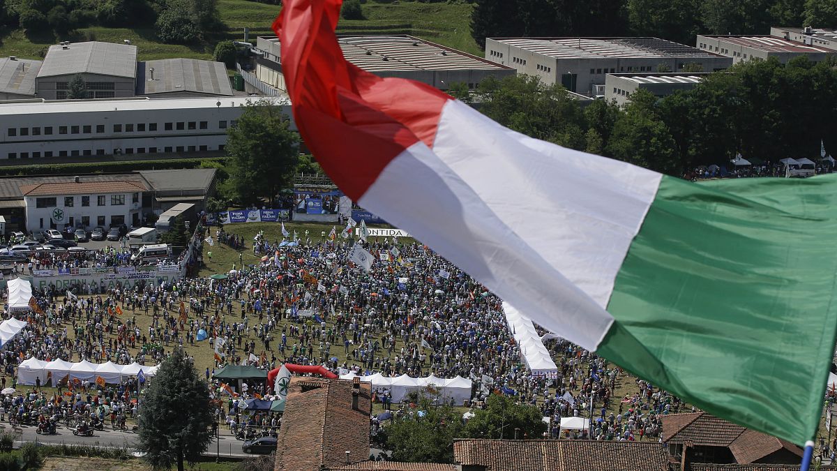A man waves the Italian flag on a hill during a the traditional League party rally in Pontida in 2018.