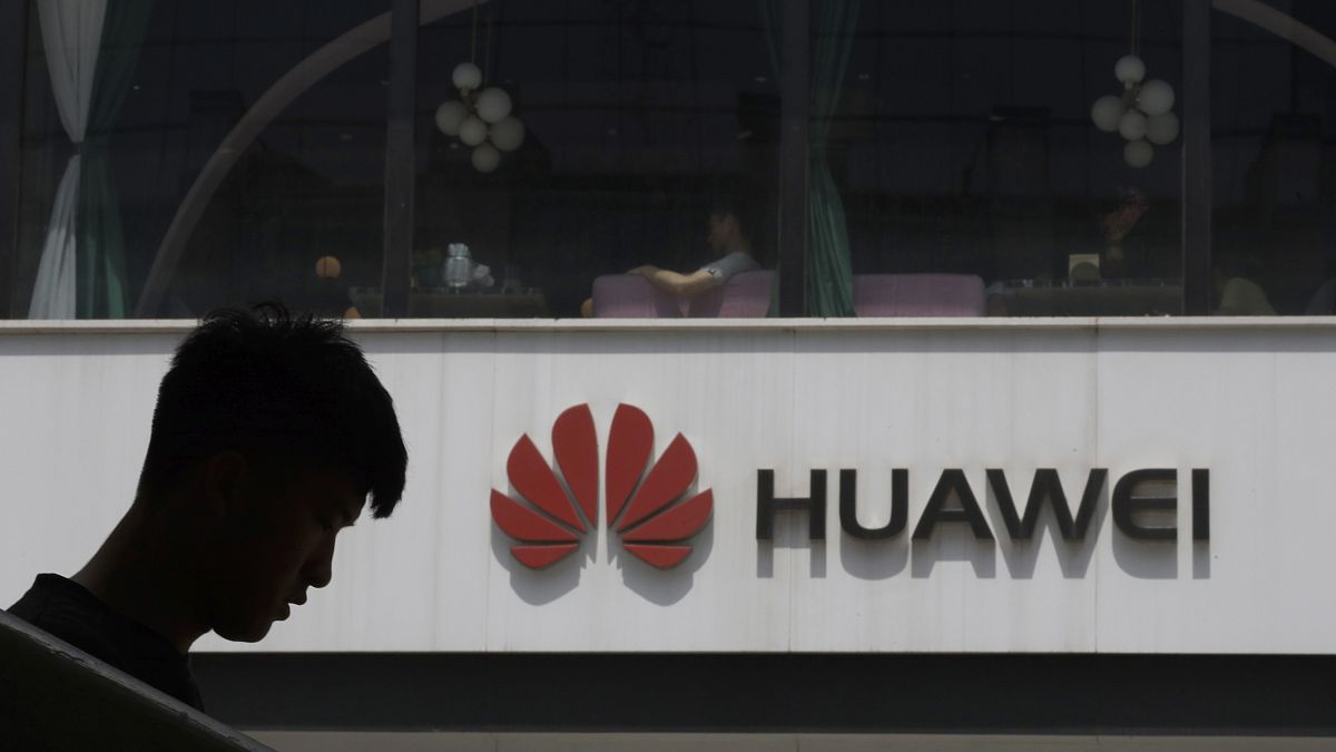 Férfi sziluettje Pekingben egy Huawei logó előtt 2019. május 16-án