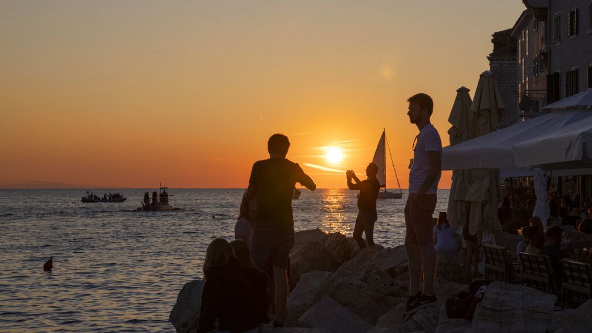 Holidaymakers enjoy the sunset on the seafront in the Adriatic town of Rovinj, Croatia, Friday, Aug. 27, 2021
