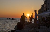 Holidaymakers enjoy the sunset on the seafront in the Adriatic town of Rovinj, Croatia, Friday, Aug. 27, 2021